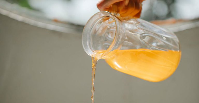 Detox Drinks - Crop woman pouring cold orange beverage into glass