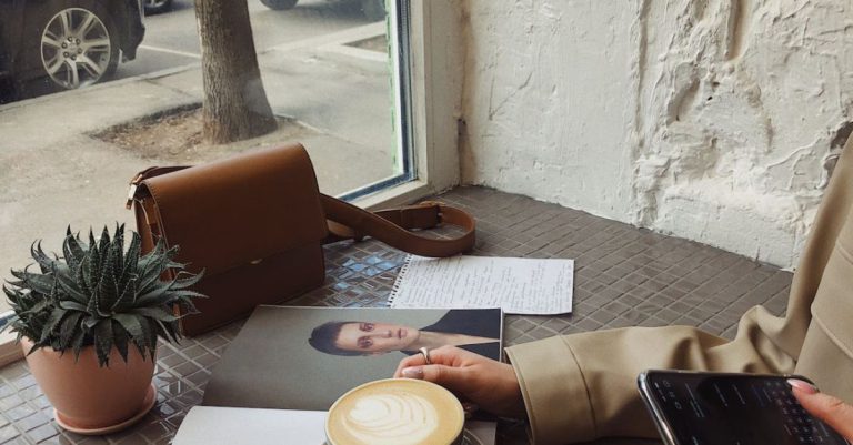 Weekend Detox - Crop of unrecognizable female tourist in casual wear surfing internet and flipping magazine while drinking coffee in sidewalk cafe