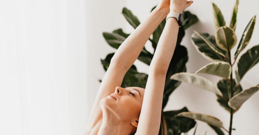 Yoga Posture - From above sporty calm female in gray sports bra performing Upward Salute exercise while practicing yoga in light living room