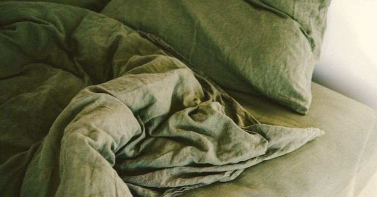Sleep Quality - A green comforter on a bed with pillows