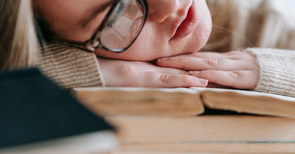Sleep Cognitive - Tired intelligent student in eyeglasses sleeping on pile of books